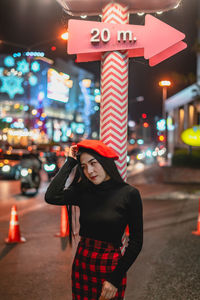 Young woman standing on illuminated street at night