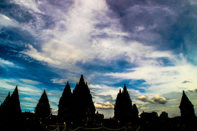 High section of silhouette built structures against cloudy sky