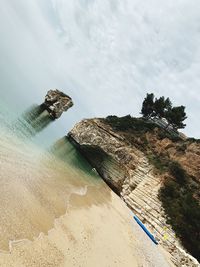 Rock formation on beach against sky