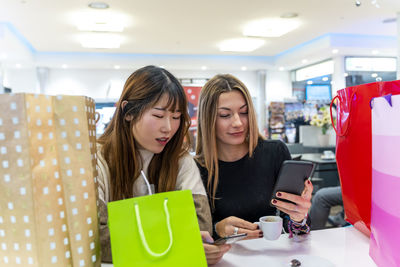 Portrait of smiling woman using mobile phone while sitting at restaurant