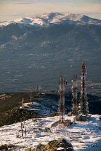 Scenic view of communication towers on snowcapped mountains against sky