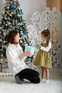 Rear view of mother and daughter decorating christmas tree