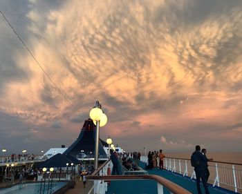 People at music concert against sky during sunset