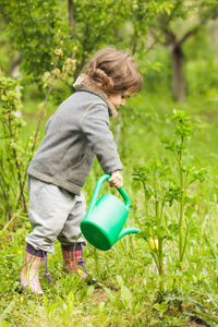 Rear view of boy holding umbrella standing by plants