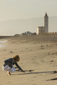 Full length of woman on beach by sea against sky