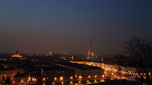 Illuminated buildings in city against clear sky at night