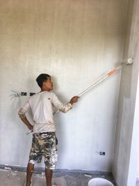 Rear view of boy standing against wall