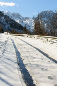 Snow covered field by mountain against sky