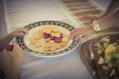 Cropped image of hand holding cake on table