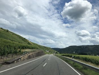 Empty road along landscape against sky