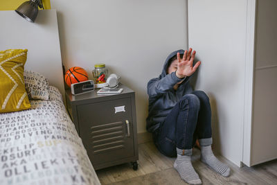 Side view of woman using mobile phone while sitting on bed at home