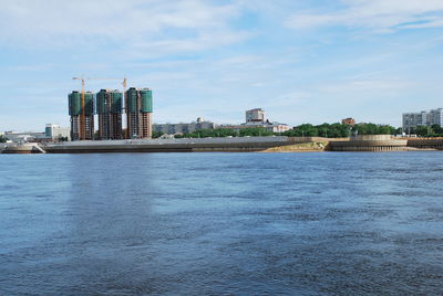 Sea by buildings against sky in city