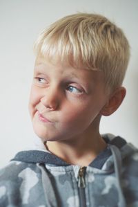 Close-up of boy making face while standing against white background