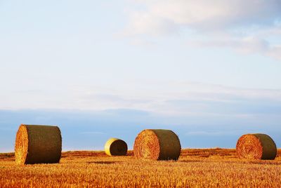 Hay bales on field against sky