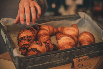 Close-up of human hand choosing croissant