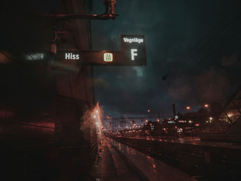 Train on illuminated street in city against sky at night