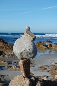 Stack of stones at beach against sky