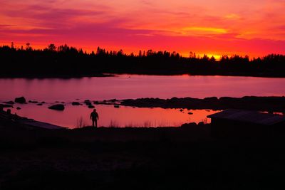 Silhouette trees by lake against sky during sunset