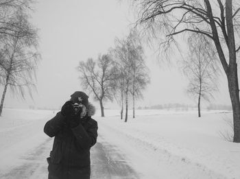 Man photographing on snow covered landscape during winter