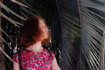 Close-up of young woman standing by tree