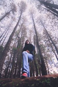 Low angle view of man amidst trees in forest