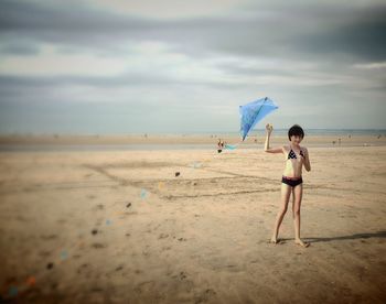 Woman standing on beach against cloudy sky