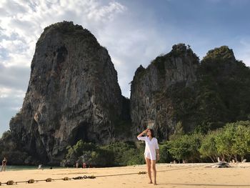 Full length of woman standing at beach against cloudy sky