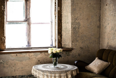 Flower vase on table by window at home