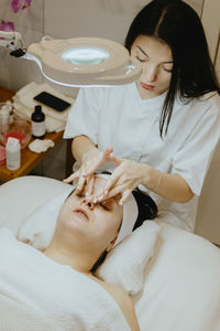 A girl cosmetologist makes a relaxing massage of a woman face.
