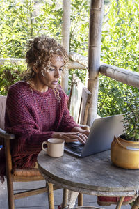 Young woman using laptop while sitting on table