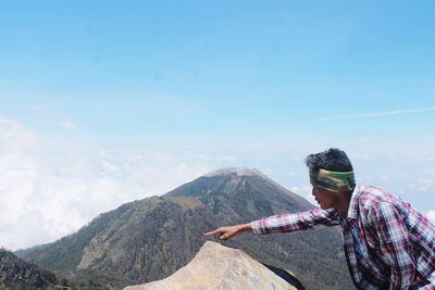 Side view of man looking at mountains against sky