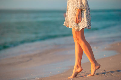 Low section of woman standing at beach