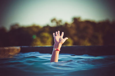 Cropped hand emerging from swimming pool