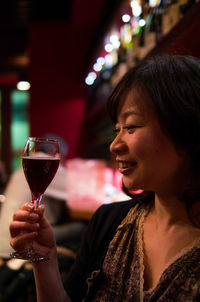 Happy woman looking at wine in wineglass