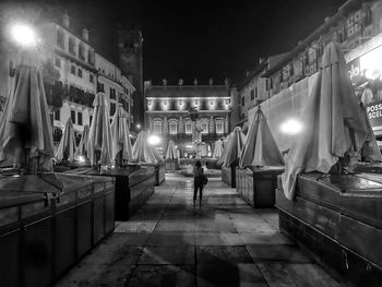 People walking on illuminated street amidst buildings at night