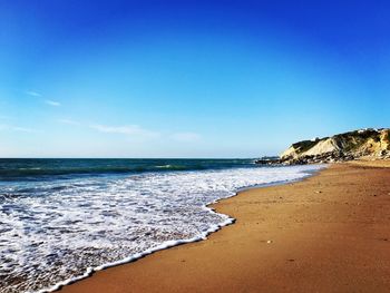 Scenic view of beach against clear blue sky