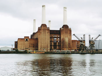 View of factory by river against sky