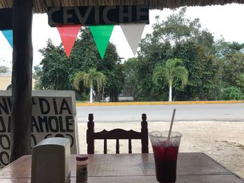 Chairs and table at sidewalk cafe against trees