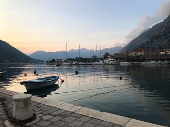 Sailboats moored at harbor against sky during sunset