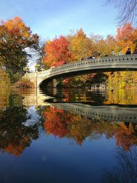Arch bridge over river against sky during autumn