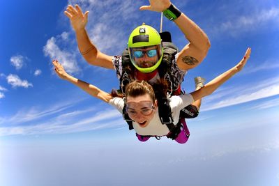 Female friends in mid-air against sky