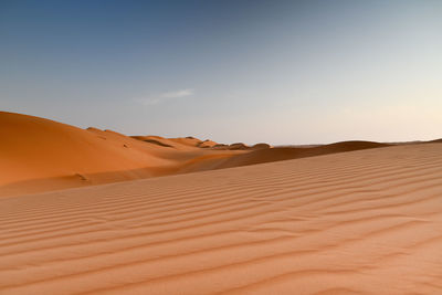 Sand dunes in desert against sky