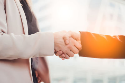 Midsection of businesswoman shaking hands with colleague