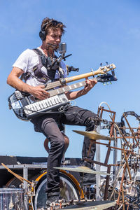 Man playing guitar against sky