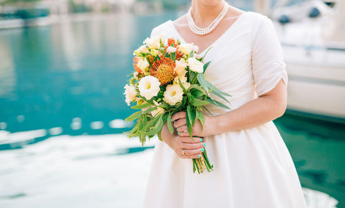 Midsection of woman holding flowering plant