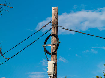 Low angle view of electricity pylon against blue sky