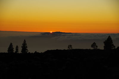 Scenic view of silhouette landscape against orange sky