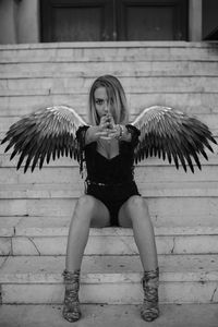Portrait of woman wearing wings while sitting on steps