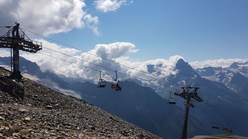 Overhead cable cars over snowcapped mountains against sky
