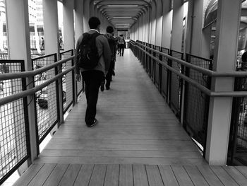 Rear view of people walking on footbridge in city